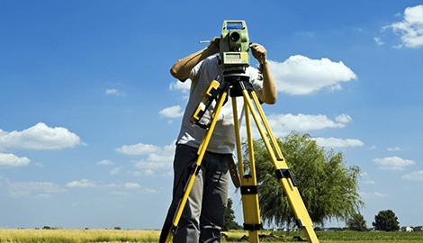 A man is using a surveying instrument to measure the ground.